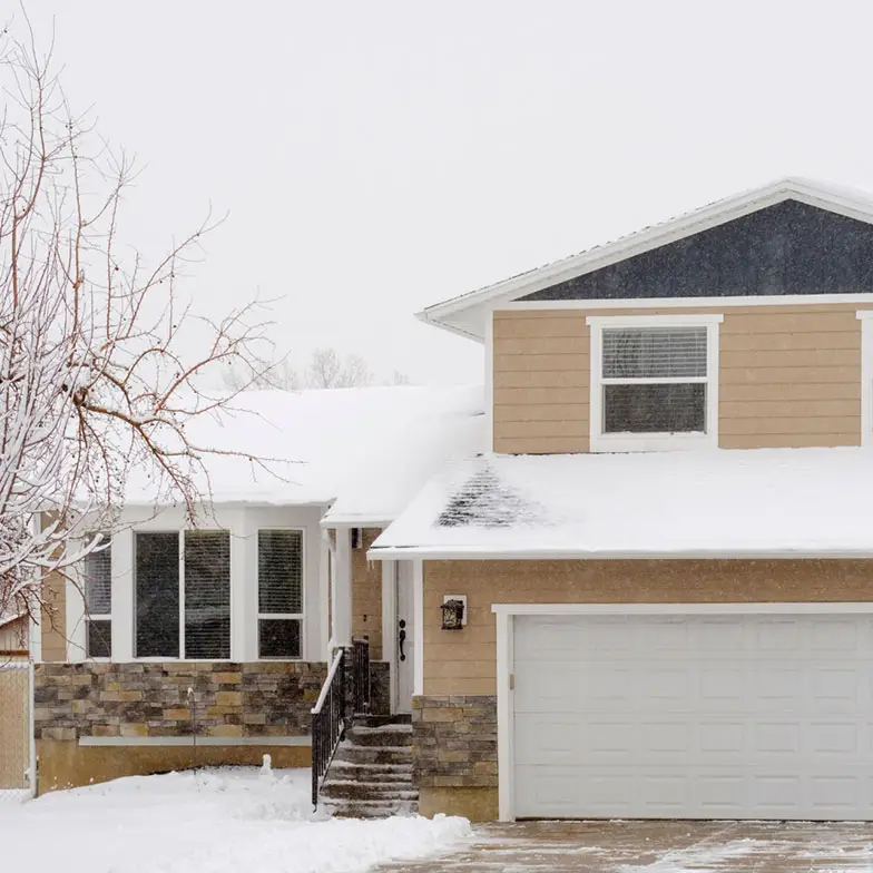 Snow shovel leaning against a house.